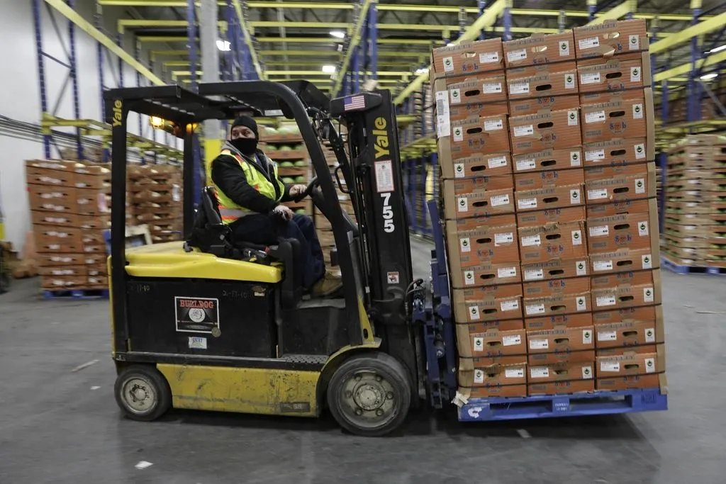 Forklift operator moving a full pallet through a warehouse